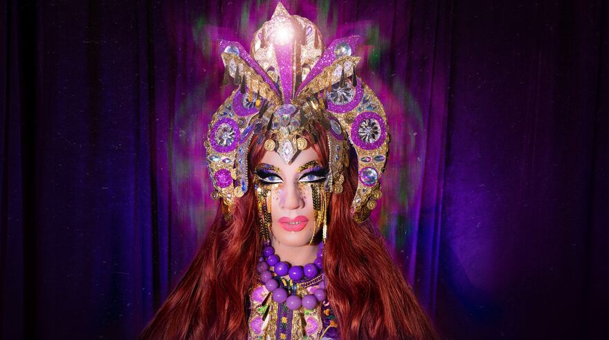Ginger Johnson with a purple and gold headpiece and purple curtains in the background