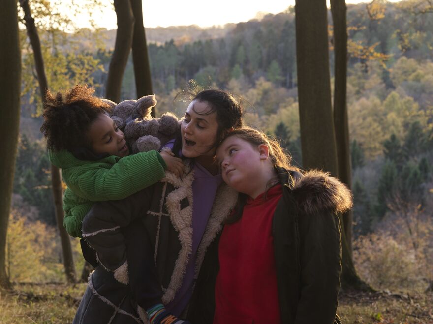 A young mother with children embracing in a woodland.