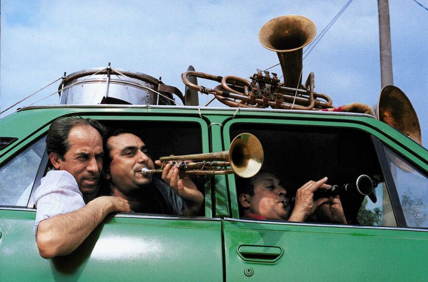 Three musicians from Fanfare Ciocărlia packed into a bright green car.