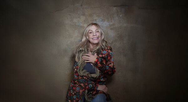 Rickie Lee Jones in a flowery coat smiling 