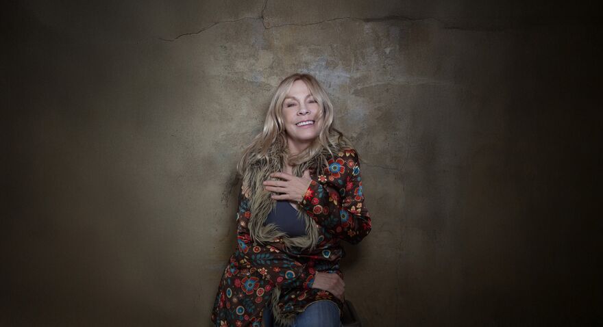 Rickie Lee Jones in a flowery coat smiling 