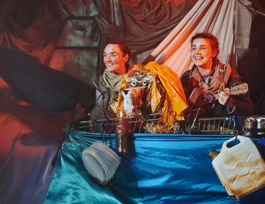 Two people on a make shift boat with a tiger puppet between them