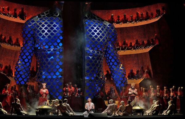 A large group of people are dwarfed on stage by a giant blue torso.  
