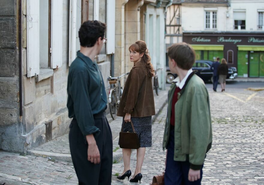 A woman turns back to look at a man along a cobbled street. 