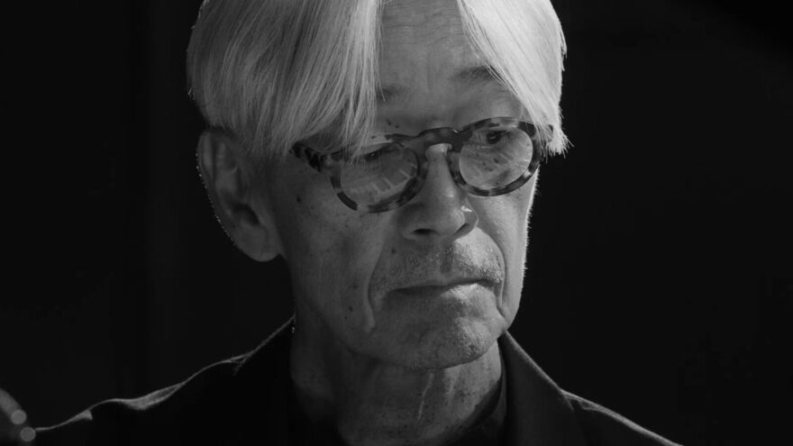 A black and white close-up of Ryuichi Sakamoto