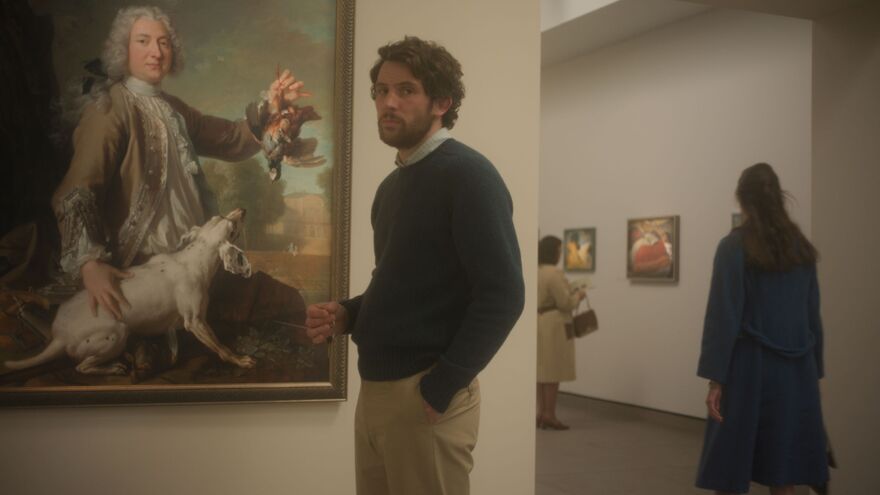 A man stands next to a painting in a gallery. 