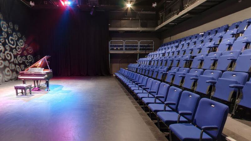 Studio Black box room with 6 rows of seats and a Steinway piano