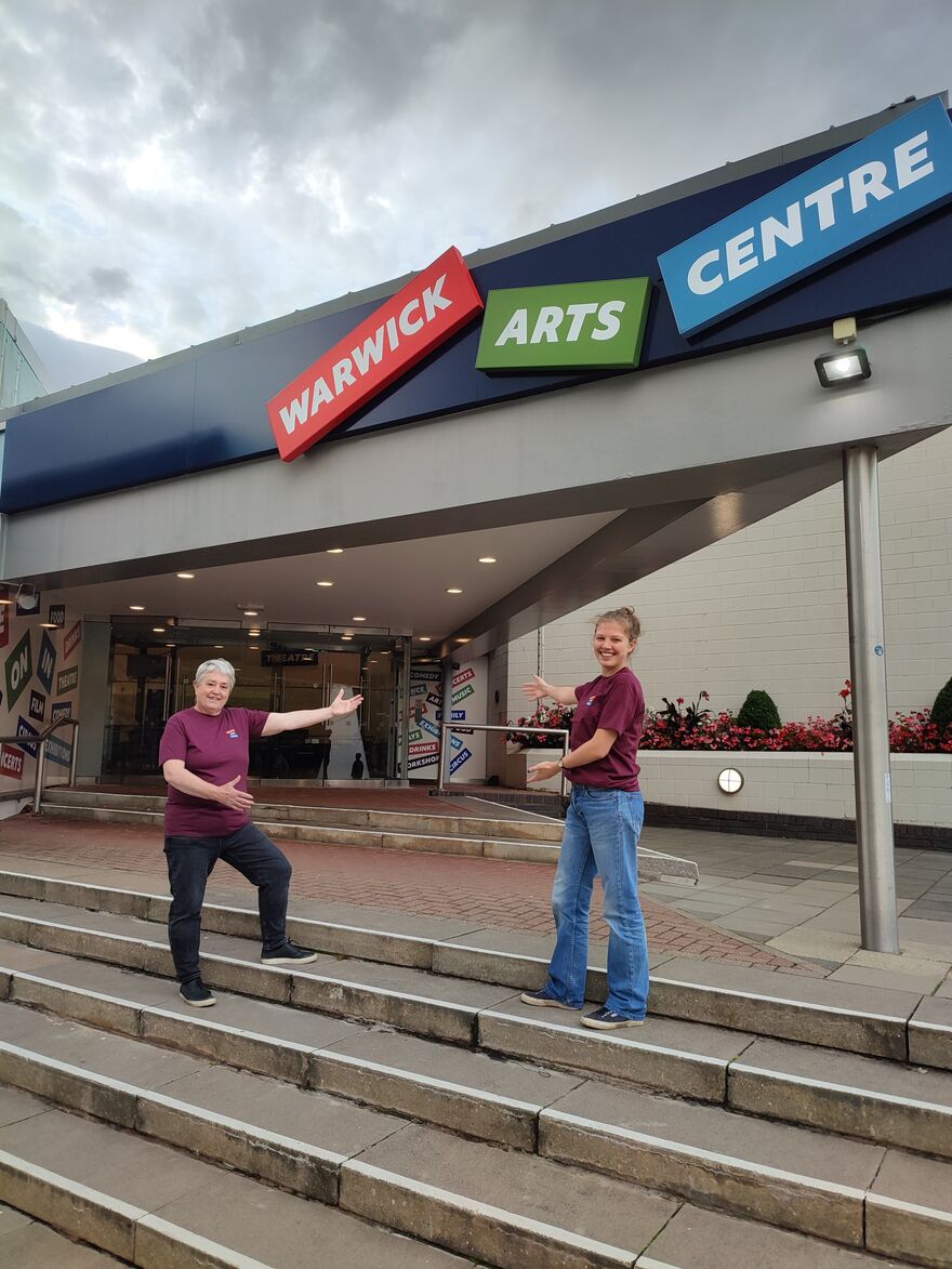Two Volunteers pointing towards the entrance of Warwick Arts Centre