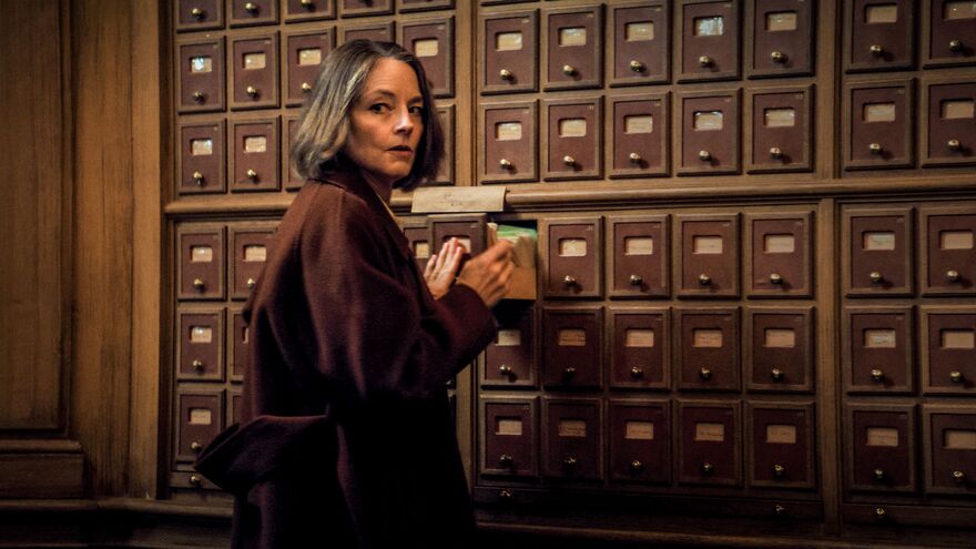 A woman looks behind her shoulder as she opens a small drawer. 