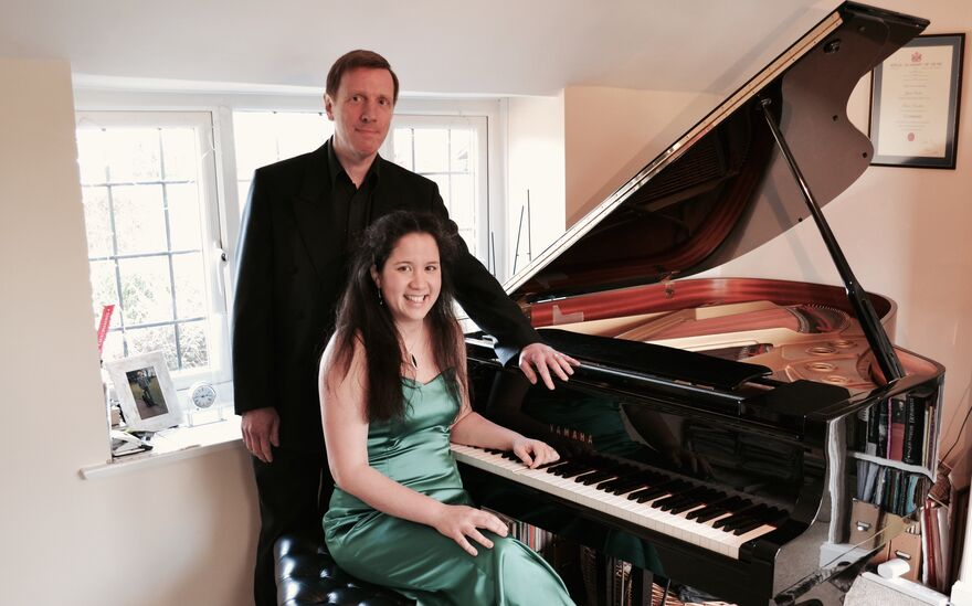 A man and woman touching a piano